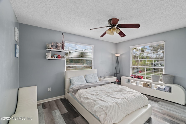 bedroom with multiple windows, ceiling fan, hardwood / wood-style flooring, and a textured ceiling