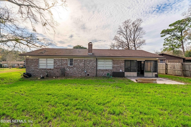 rear view of house featuring a sunroom, a patio area, and a lawn