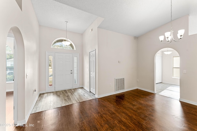 entryway with high vaulted ceiling, a chandelier, hardwood / wood-style floors, and a textured ceiling