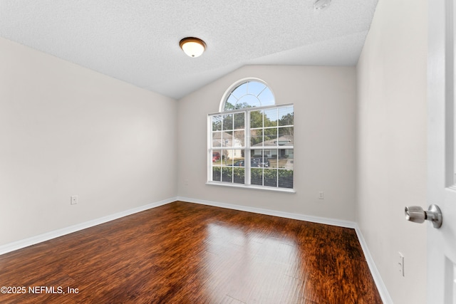 unfurnished room featuring dark wood-type flooring, a textured ceiling, and vaulted ceiling