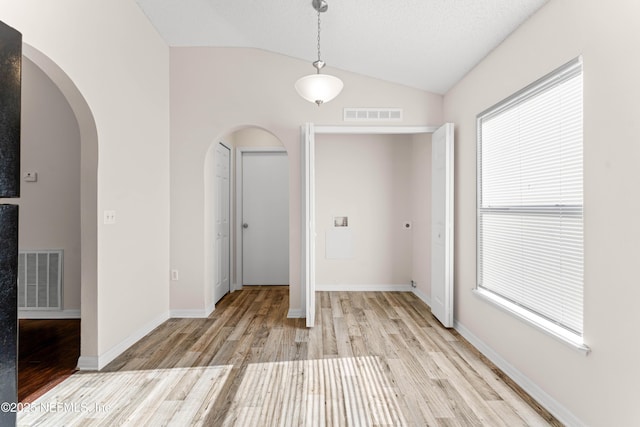 interior space with lofted ceiling, a textured ceiling, and light wood-type flooring