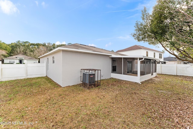 rear view of house with central AC, a lawn, and a sunroom