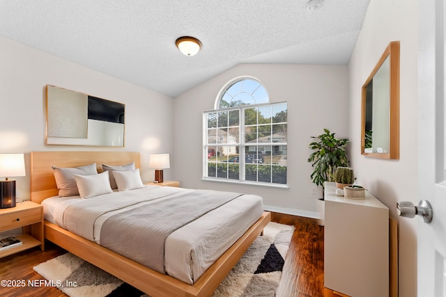 bedroom with dark wood-type flooring, vaulted ceiling, and a textured ceiling