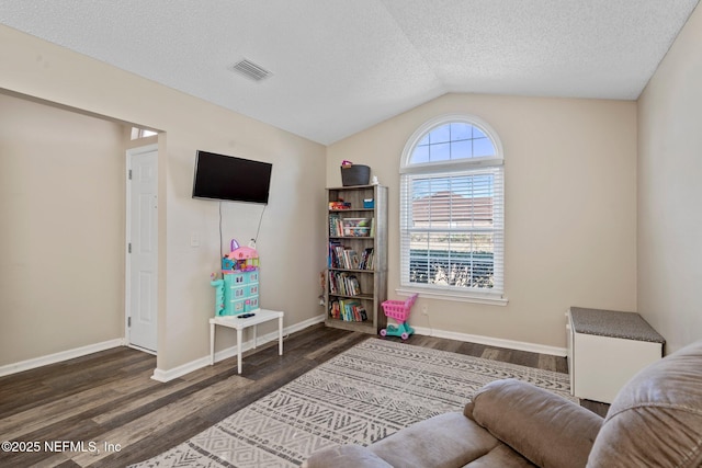 sitting room featuring lofted ceiling, dark hardwood / wood-style floors, and a textured ceiling