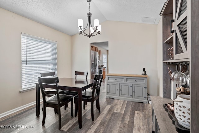 dining room featuring a textured ceiling, vaulted ceiling, dark hardwood / wood-style floors, and a chandelier