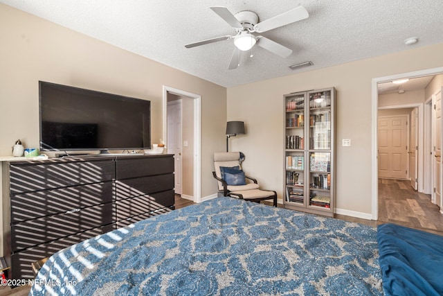 bedroom featuring dark hardwood / wood-style flooring, ceiling fan, and a textured ceiling