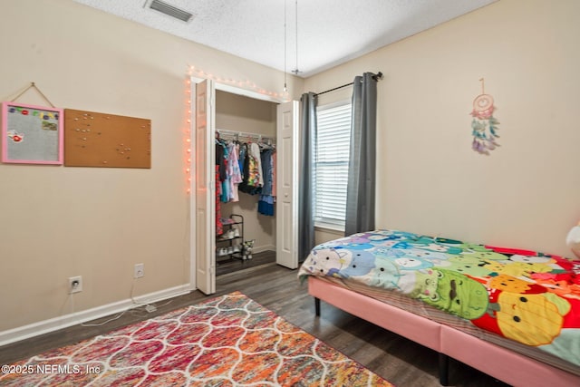 bedroom featuring dark wood-type flooring, a closet, and a textured ceiling