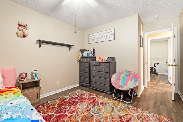 bedroom with ceiling fan, dark hardwood / wood-style floors, and a textured ceiling