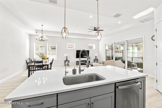 kitchen with gray cabinets, a raised ceiling, and a center island with sink