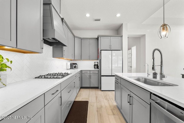 kitchen featuring sink, premium range hood, gray cabinetry, hanging light fixtures, and stainless steel appliances