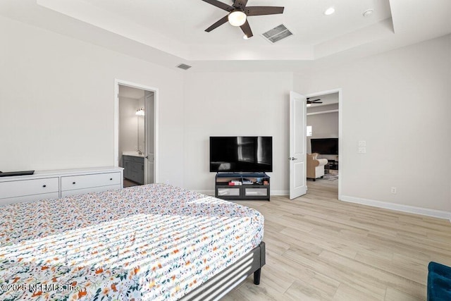 bedroom with ceiling fan, a raised ceiling, and light wood-type flooring