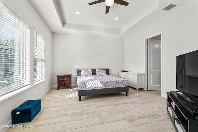 bedroom with a tray ceiling, light hardwood / wood-style flooring, and ceiling fan