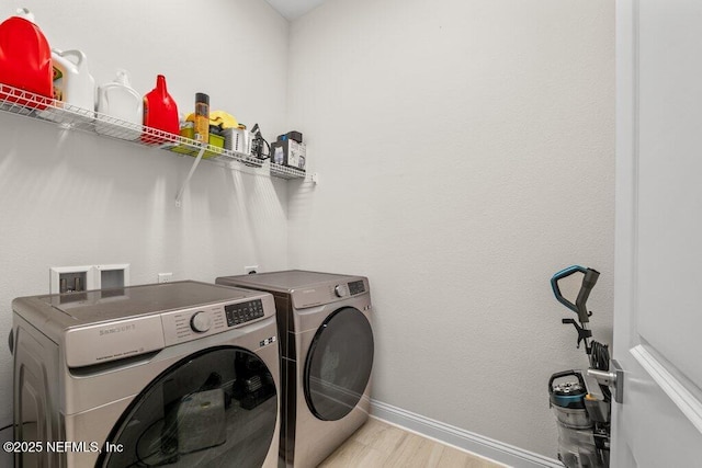 clothes washing area featuring washer and dryer and light hardwood / wood-style flooring