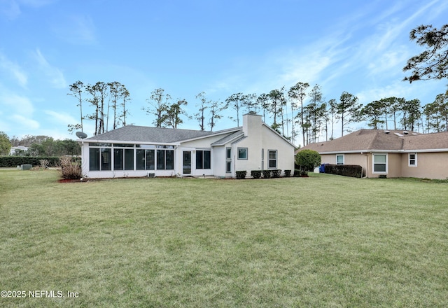 rear view of house with a yard and a sunroom