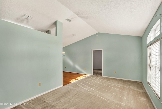 spare room with lofted ceiling, light carpet, and a textured ceiling