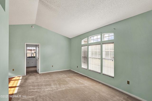 carpeted empty room featuring vaulted ceiling, a textured ceiling, and a wealth of natural light