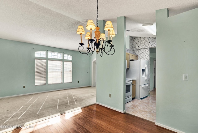 unfurnished dining area featuring an inviting chandelier, a textured ceiling, and light wood-type flooring