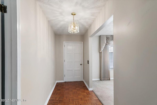 hall with baseboards and an inviting chandelier