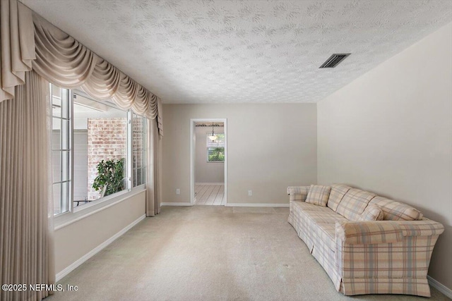 unfurnished room with baseboards, carpet flooring, a textured ceiling, and visible vents