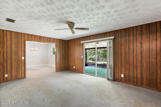 unfurnished room featuring plenty of natural light, wooden walls, and visible vents