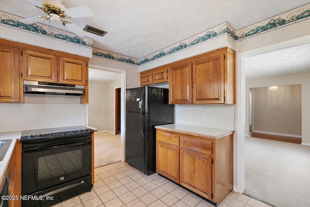 kitchen with visible vents, brown cabinets, light countertops, black appliances, and under cabinet range hood