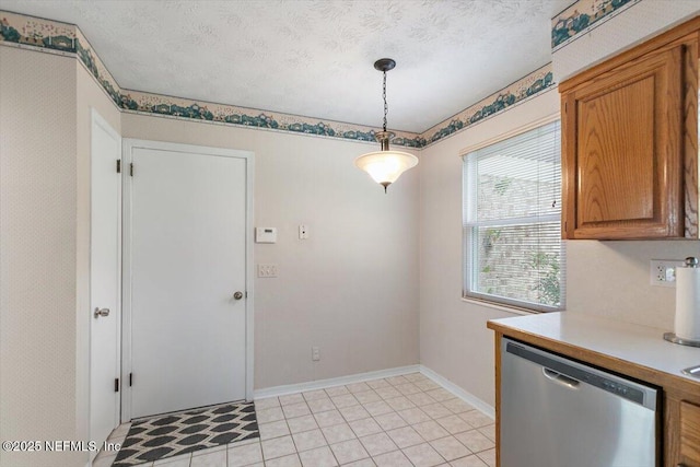 kitchen featuring stainless steel dishwasher, decorative light fixtures, brown cabinetry, and light countertops