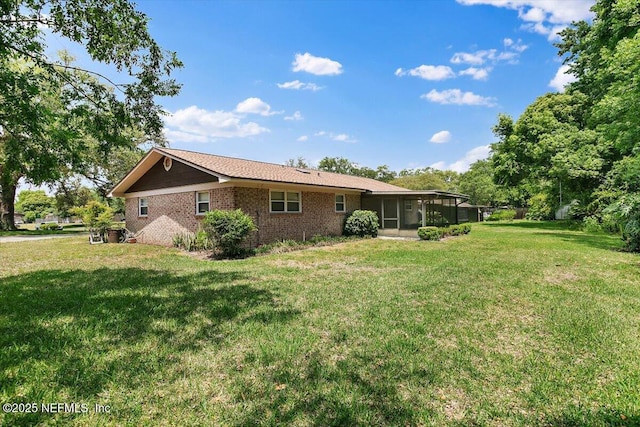 back of house with a yard, brick siding, and a sunroom