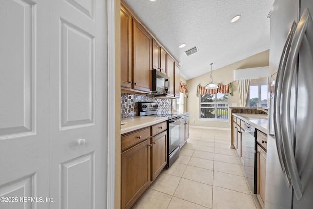 kitchen with pendant lighting, light tile patterned floors, lofted ceiling, appliances with stainless steel finishes, and decorative backsplash