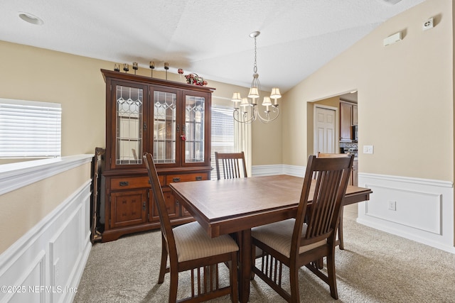 carpeted dining room featuring an inviting chandelier, vaulted ceiling, and a textured ceiling