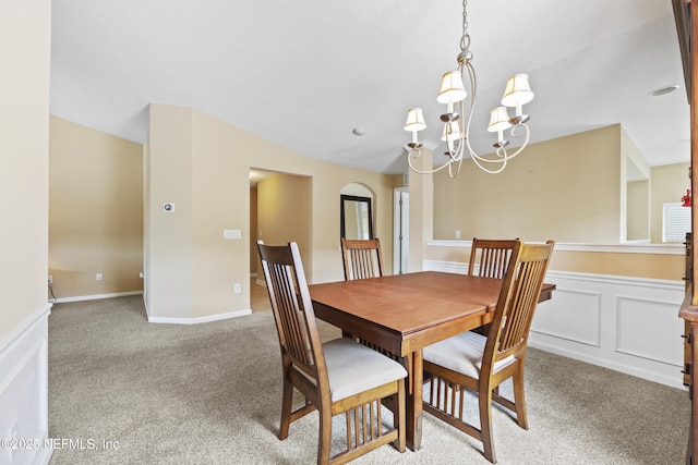 dining area featuring light colored carpet, a chandelier, and vaulted ceiling