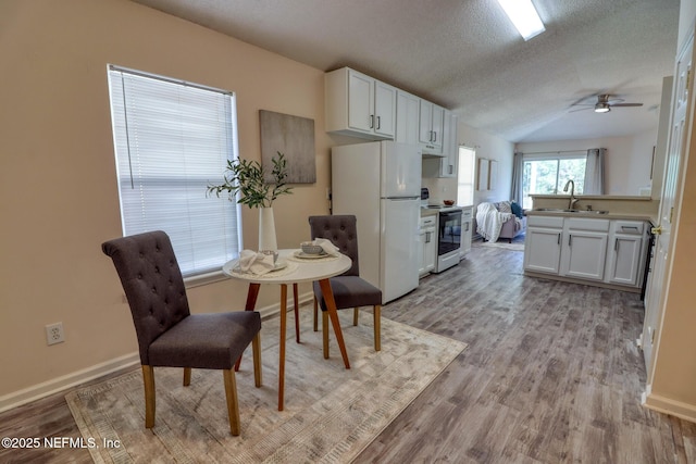 kitchen with sink, white cabinetry, range with electric cooktop, white refrigerator, and light hardwood / wood-style floors