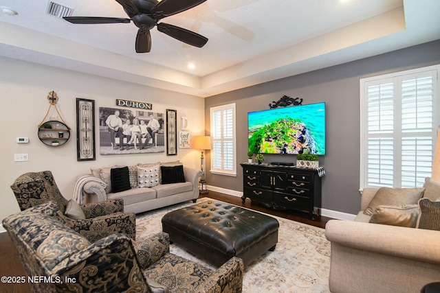 living room featuring ceiling fan, a raised ceiling, and hardwood / wood-style floors