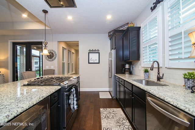 kitchen featuring pendant lighting, sink, backsplash, stainless steel appliances, and light stone countertops