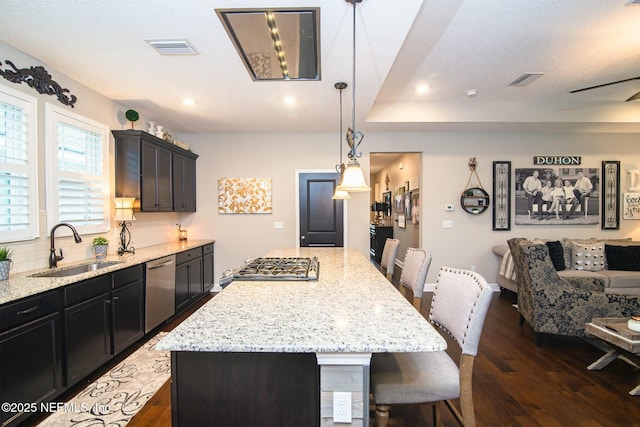 kitchen featuring sink, a breakfast bar, stainless steel appliances, a center island, and decorative light fixtures