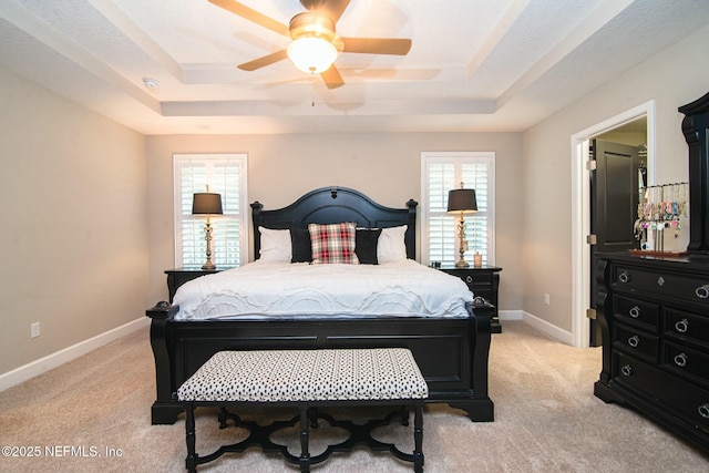 bedroom featuring ceiling fan, a tray ceiling, and light carpet