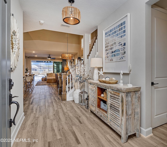 hall with a textured ceiling and light hardwood / wood-style flooring