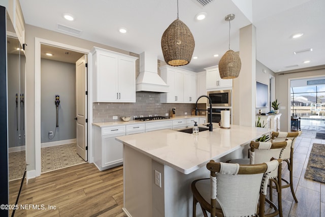 kitchen with sink, stainless steel appliances, white cabinets, and premium range hood