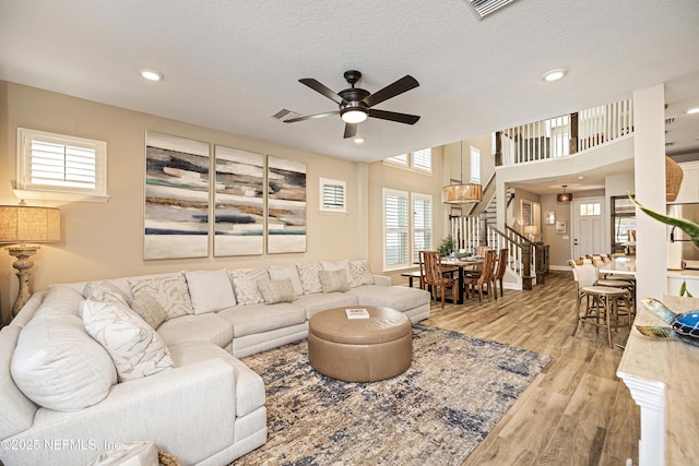 living room with ceiling fan, light hardwood / wood-style floors, and a textured ceiling