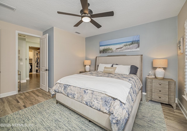 bedroom with ceiling fan, hardwood / wood-style floors, and a textured ceiling