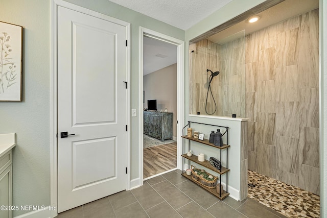 bathroom with vanity, tiled shower, tile patterned floors, and a textured ceiling