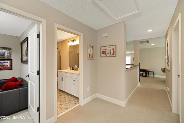 hallway featuring light colored carpet and a textured ceiling