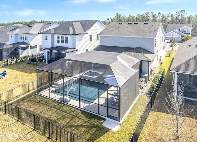 rear view of property featuring a pool with hot tub, a yard, a lanai, and a patio area