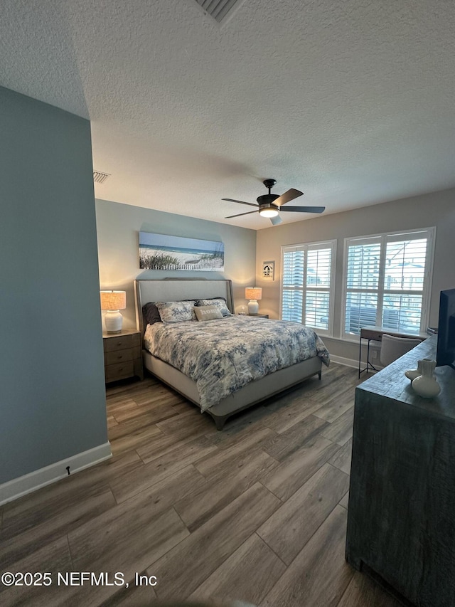 bedroom featuring a textured ceiling, baseboards, and wood finished floors