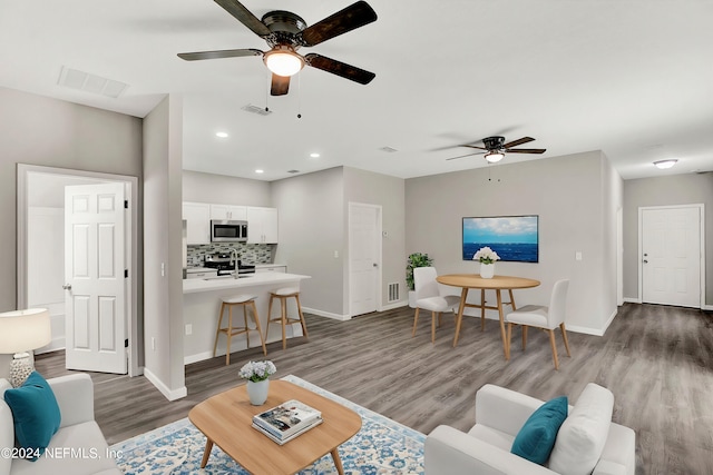 living area featuring dark wood-type flooring, recessed lighting, visible vents, and baseboards