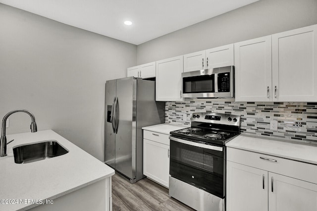 kitchen with stainless steel appliances, light countertops, a sink, and white cabinetry