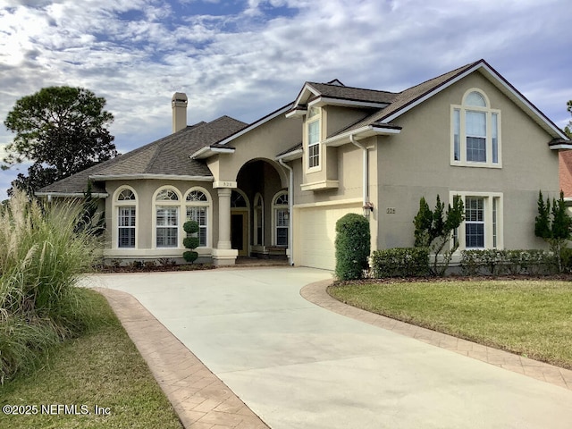 view of front of home with concrete driveway, roof with shingles, stucco siding, a front lawn, and a chimney