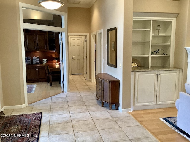 hallway with baseboards and light tile patterned floors