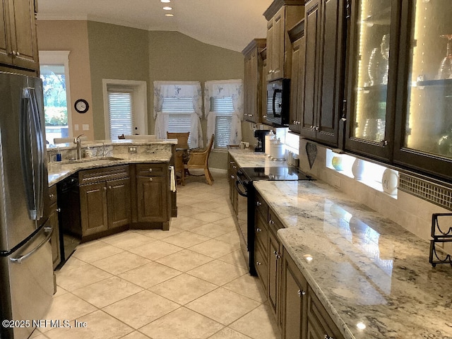 kitchen featuring light tile patterned floors, light stone counters, a sink, vaulted ceiling, and black appliances