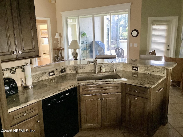 kitchen featuring backsplash, light tile patterned flooring, a sink, light stone countertops, and dishwasher