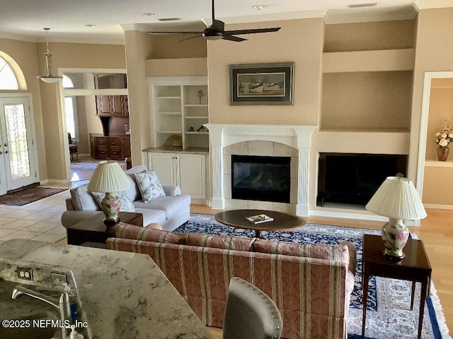 living area featuring built in shelves, a tile fireplace, french doors, and baseboards